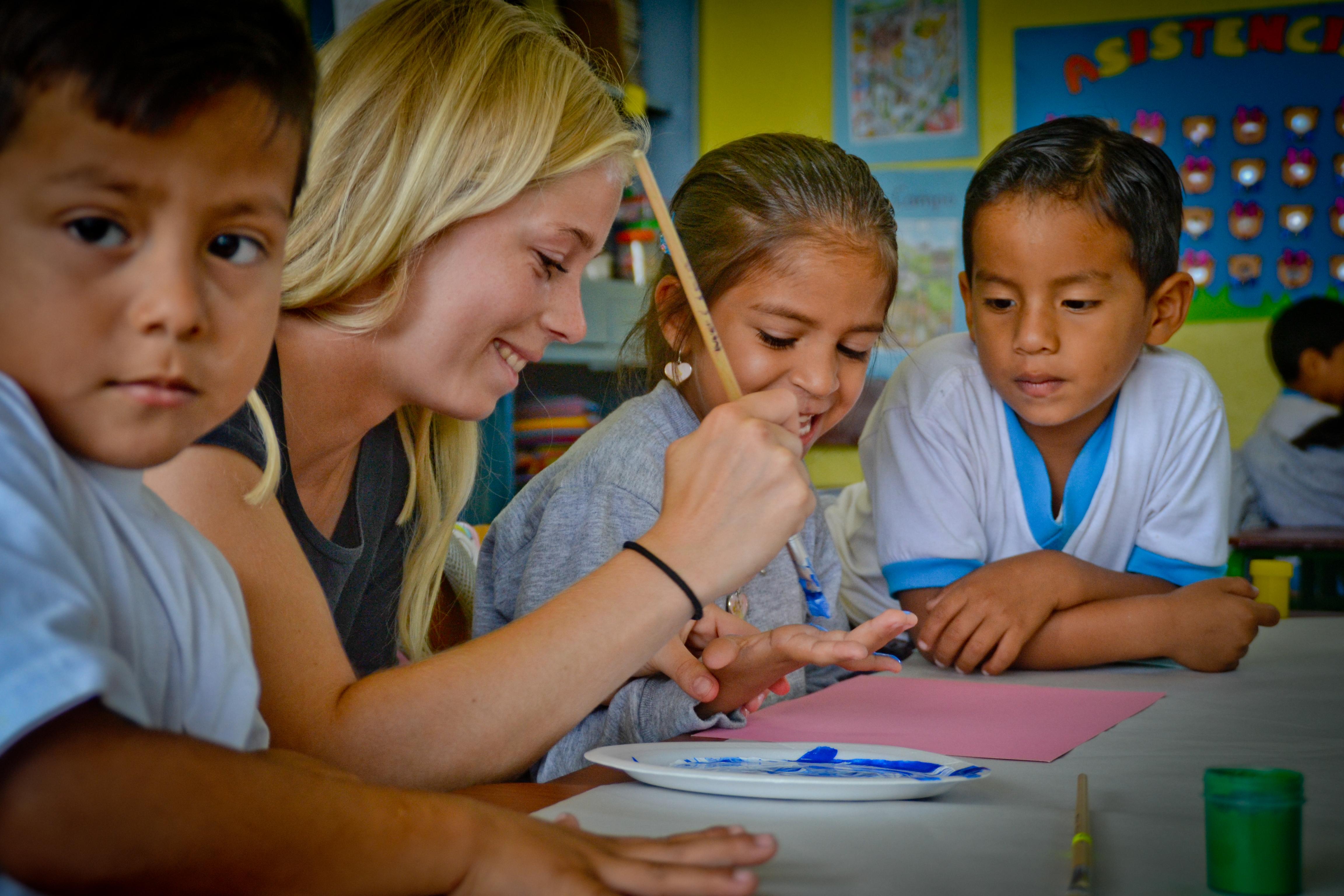 Projects Abroad teacher helps her students with their painting during her teaching work experience in Ecuador A volunteer teaching in Ecuador helps her students with the arts project